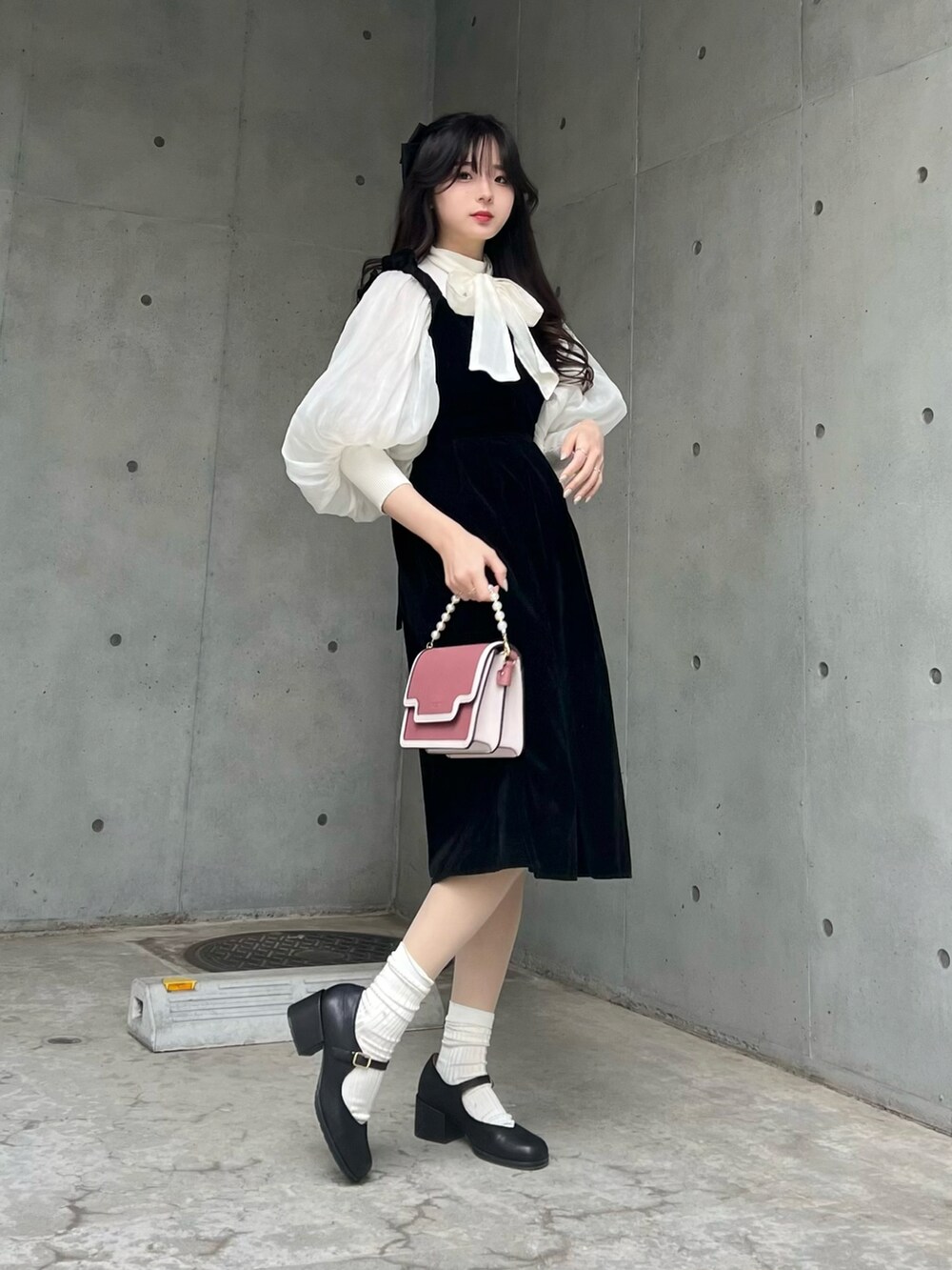 ブラック系のパンプス、ブラック系のジャンパースカート、ホワイト系のシャツ/ブラウスを着用したレディースの冬コーディネートの3枚目の写真