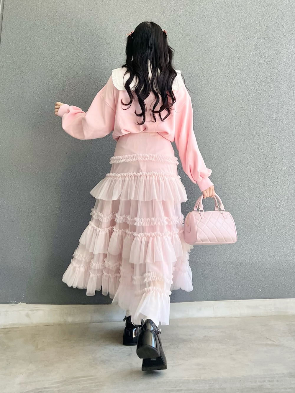 ブラック系のパンプス、ピンク系のバッグ、ピンク系のスウェットを着用したレディースの春コーディネートの4枚目の写真