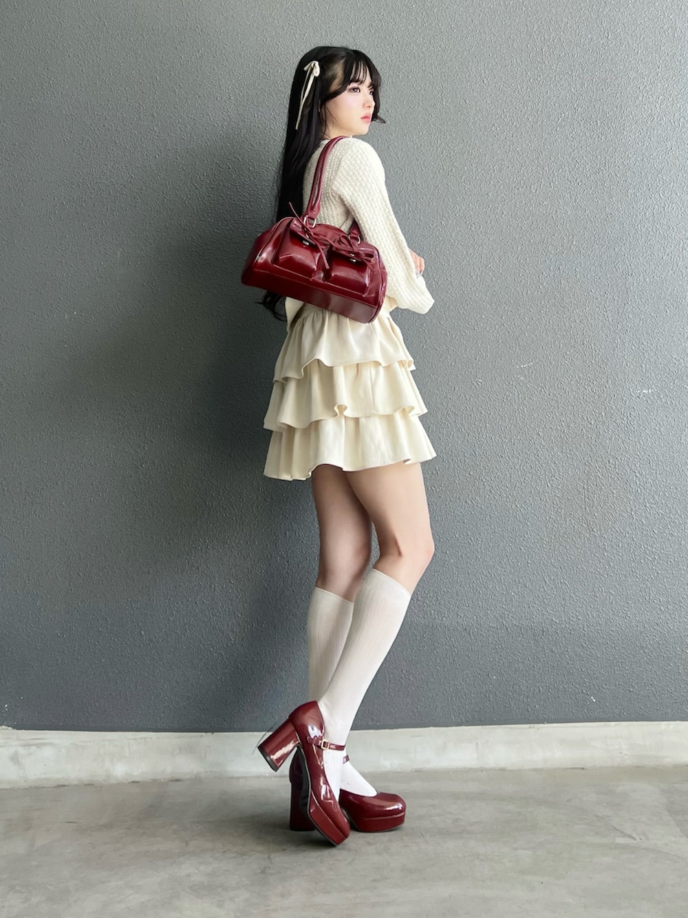 ホワイト系のスカート、ホワイト系のカーディガン/ボレロ、レッド系のパンプスを着用したレディースの秋コーディネートの2枚目の写真
