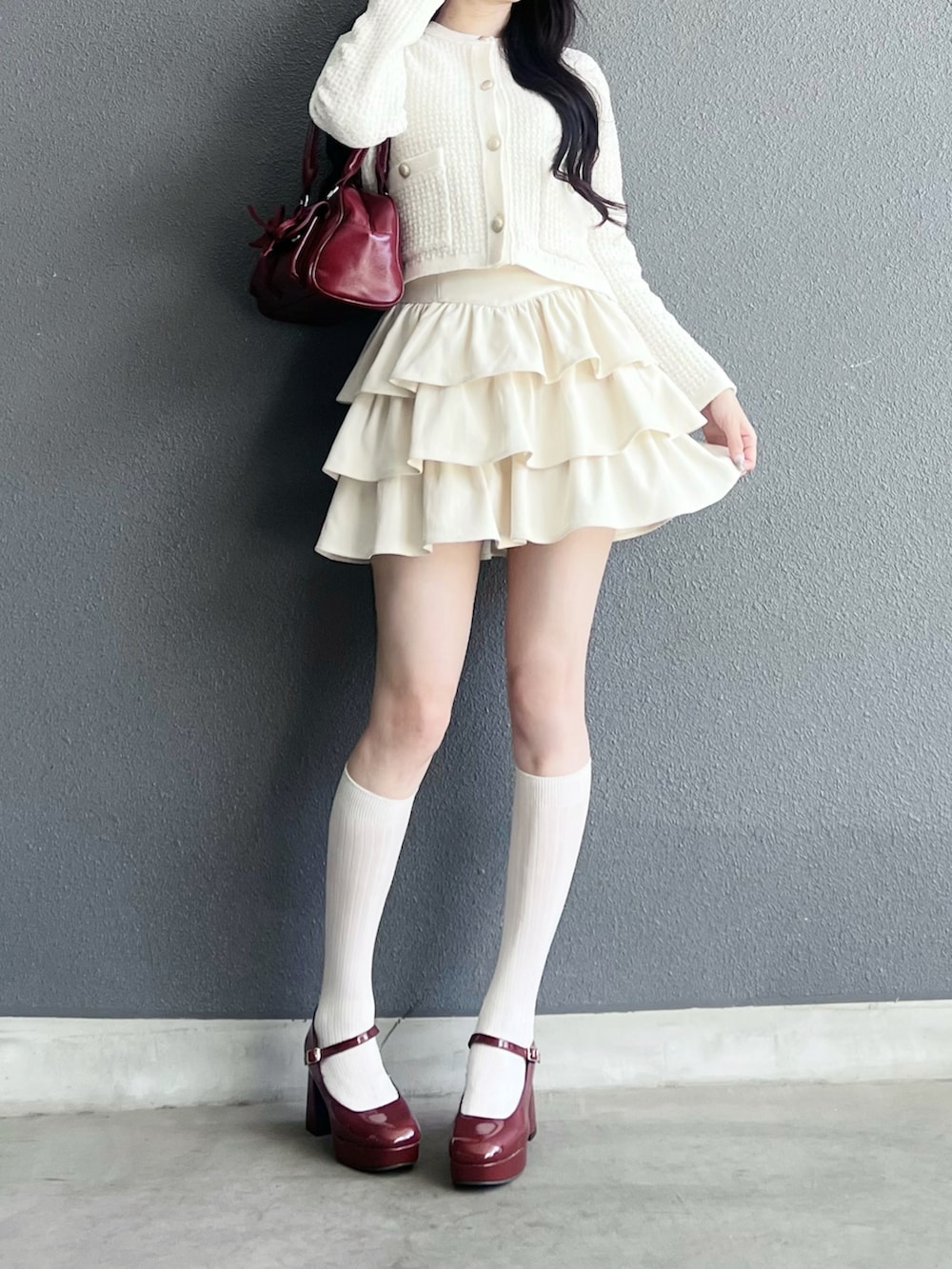 ホワイト系のスカート、ホワイト系のカーディガン/ボレロ、レッド系のパンプスを着用したレディースの秋コーディネートの4枚目の写真