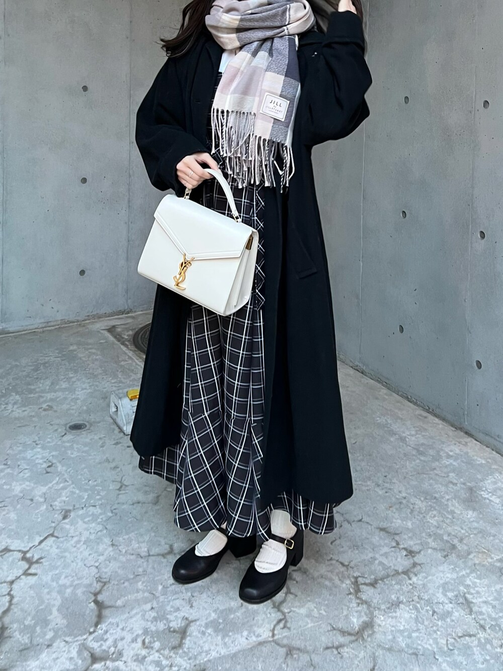 ブラック系のジャンパースカート、ブラック系のパンプス、グレー系のマフラーを着用したレディースの冬コーディネートの3枚目の写真