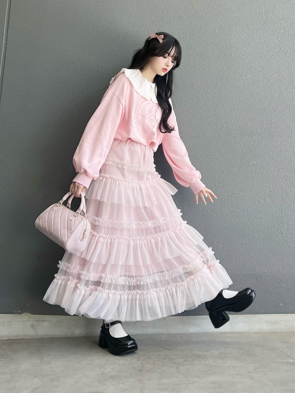 ブラック系のパンプス、ピンク系のバッグ、ピンク系のスウェットを着用したレディースの春コーディネートの2枚目の写真