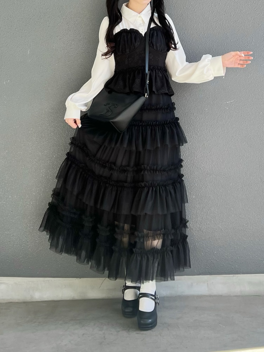 ブラック系のスカート、ブラック系のトップス、ブラック系のパンプスを着用したレディースの春コーディネートの3枚目の写真