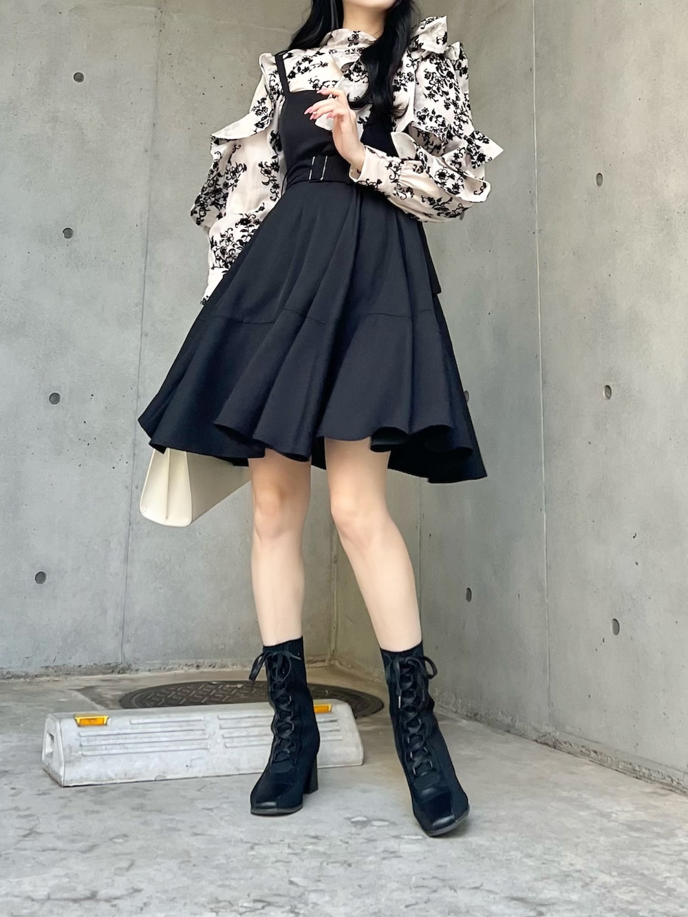 ブラック系のジャンパースカート、ブラック系のシャツ/ブラウス、ブラック系のブーツを着用したレディースの秋コーディネートの2枚目の写真