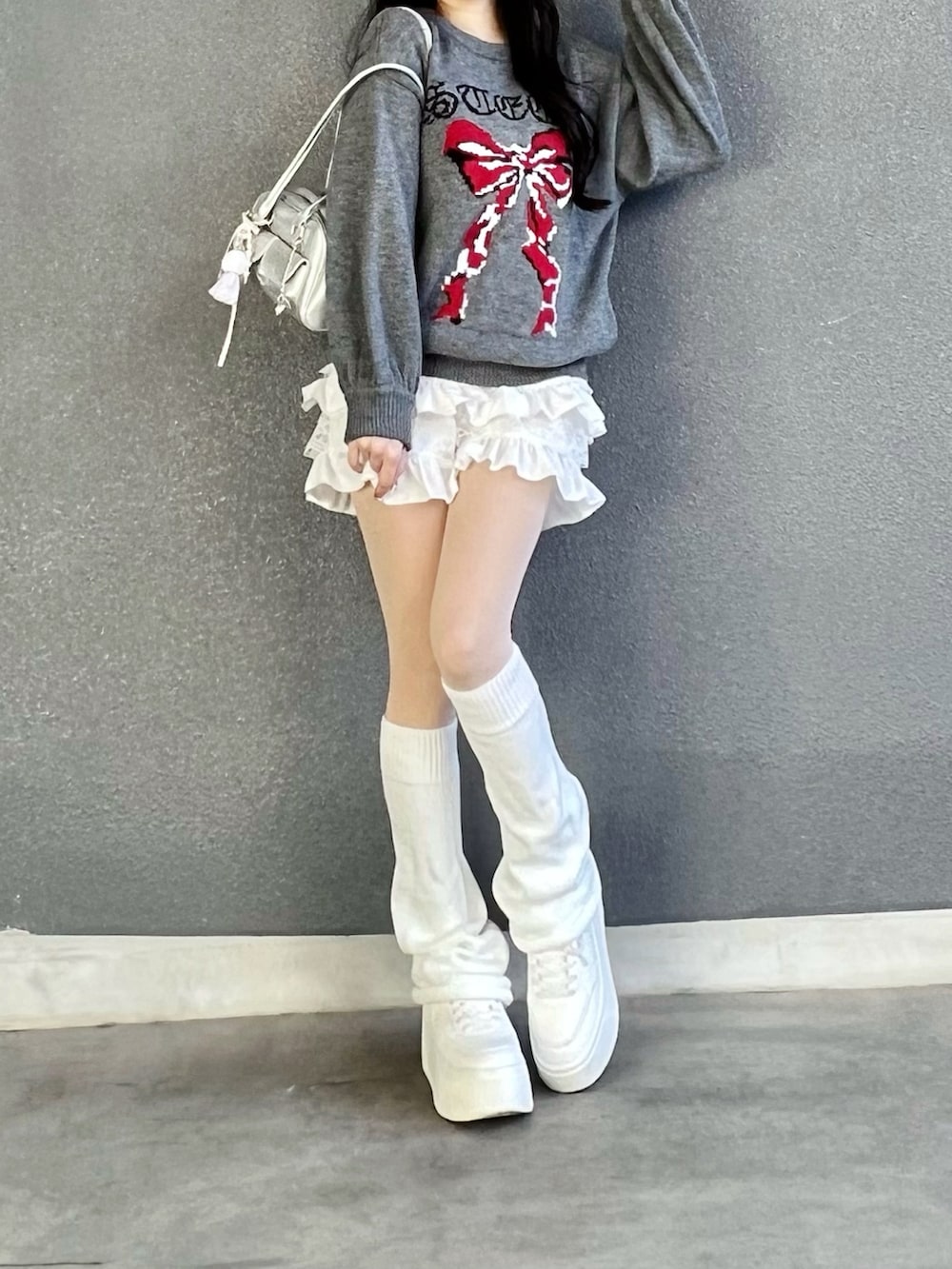 グレー系のニット/セーター、ホワイト系のパンツ、シルバー系のバッグを着用したレディースの冬コーディネートの4枚目の写真