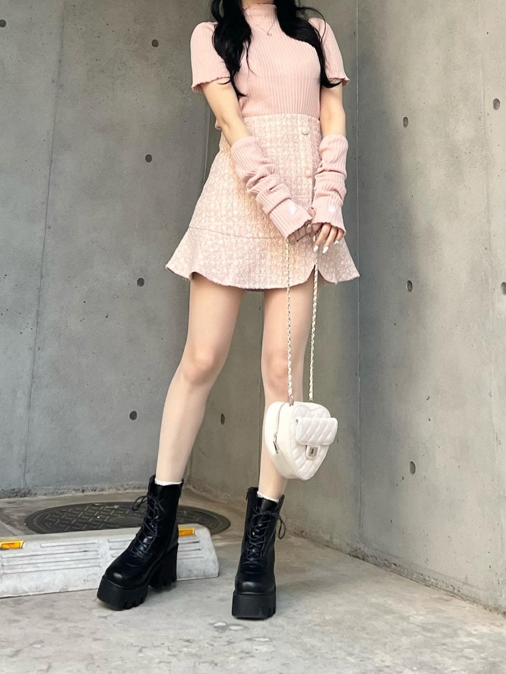 ピンク系のスカート、ピンク系のTシャツ/カットソー、ブラック系のブーツを着用したレディースの春コーディネートの2枚目の写真