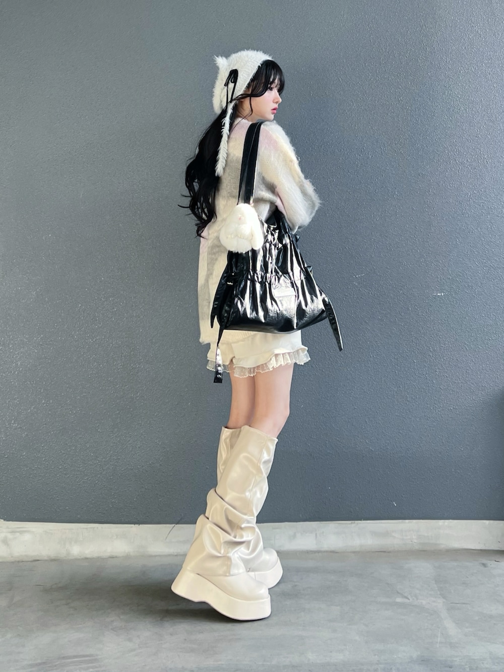 グレー系のニット/セーター、ホワイト系のその他パンツ、ホワイト系のブーツを着用したレディースの秋コーディネートの2枚目の写真