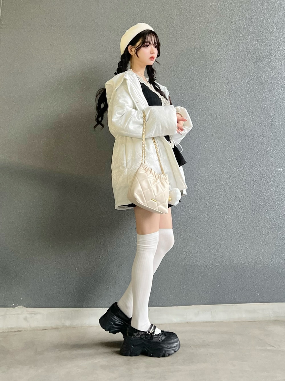 ブラック系のスカート、ブラック系のトップス、ホワイト系のバッグを着用したレディースの冬コーディネートの2枚目の写真