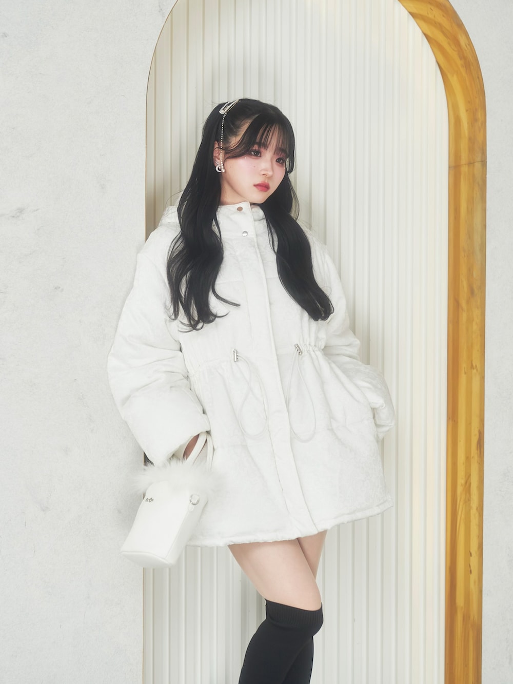 ホワイト系のジャケット/アウター、ホワイト系のバッグ、ブラック系のブーツを着用したレディースの冬コーディネートの3枚目の写真