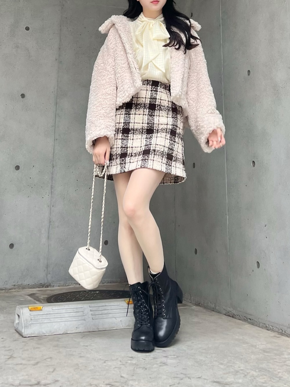 ベージュ系のスカート、ホワイト系のブルゾン、ブラック系のブーツを着用したレディースの冬コーディネートの2枚目の写真