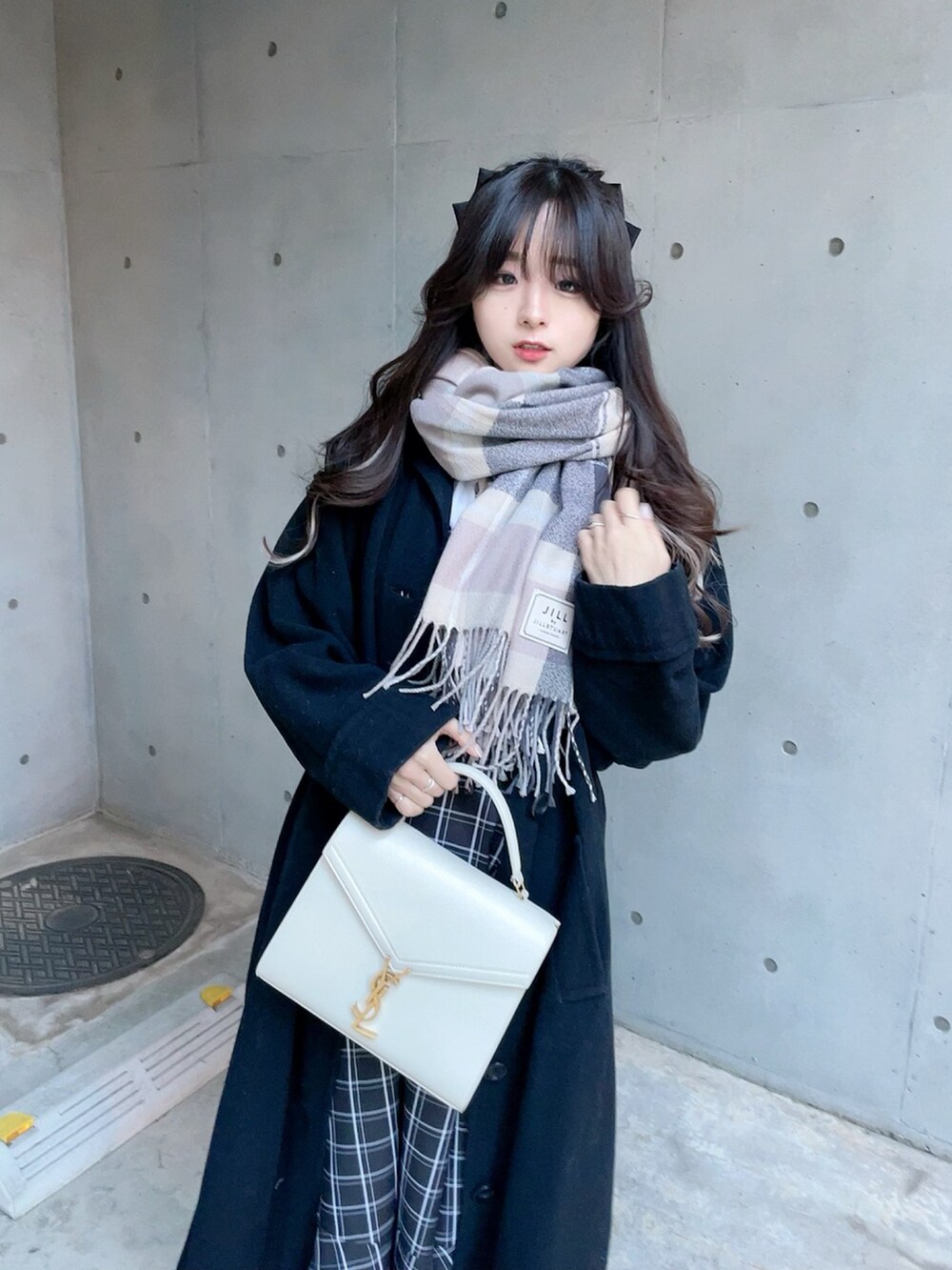 ブラック系のジャンパースカート、ブラック系のパンプス、グレー系のマフラーを着用したレディースの冬コーディネートの4枚目の写真