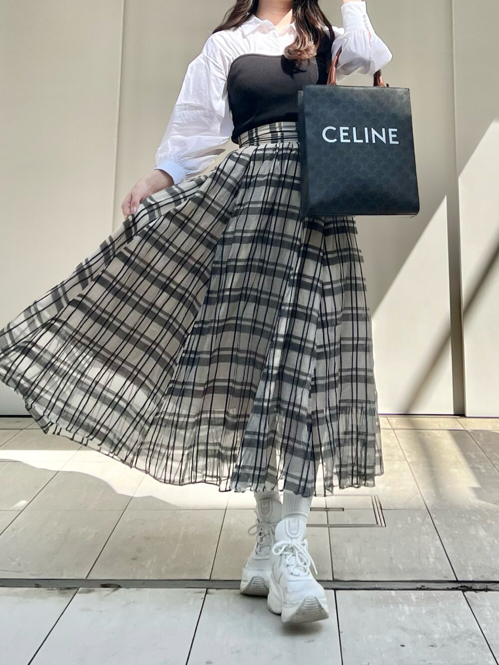 ブラック系のニット/セーター、ホワイト系のスカートを着用したレディースの春コーディネートの3枚目の写真