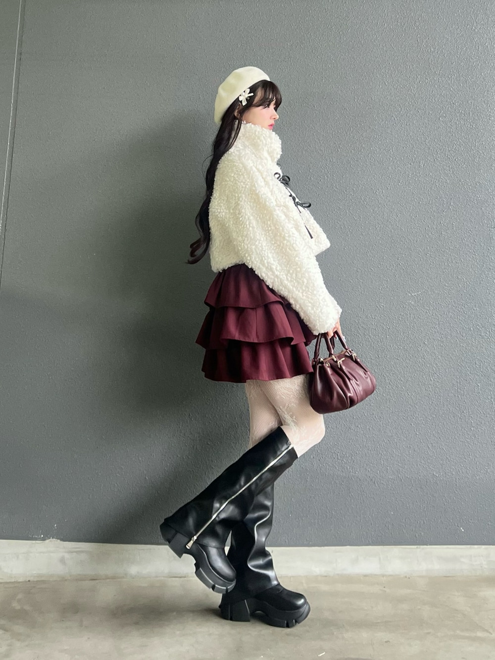 レッド系のバッグ、ブラック系のブーツ、ホワイト系のその他アウターを着用したレディースの秋コーディネートの3枚目の写真