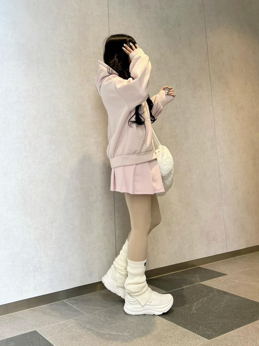 ピンク系のパーカー、ホワイト系のショルダーバッグ、ホワイト系のスニーカーを着用したレディースの春コーディネートの3枚目の写真