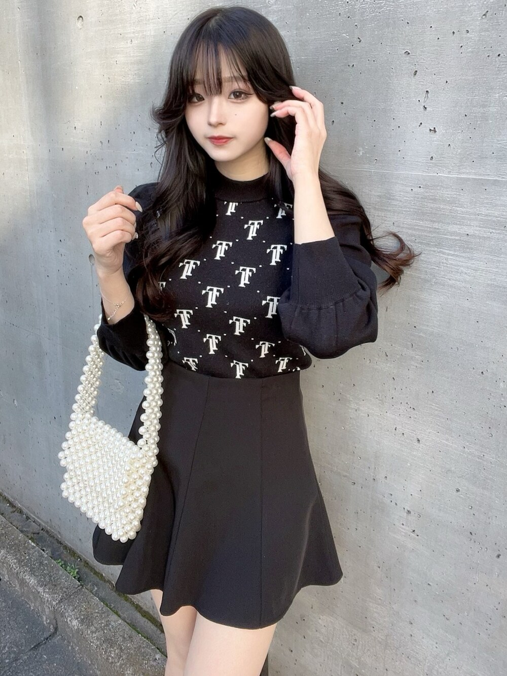 ブラック系のニット/セーター、ブラック系のスカート、ブラック系のブーツを着用したレディースの秋コーディネートの2枚目の写真