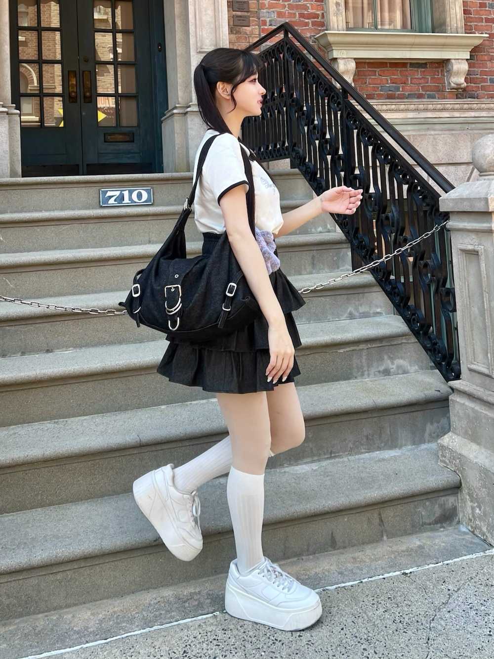 ホワイト系のシューズ、ブラック系のスカート、ブラック系のショルダーバッグを着用したレディースの春コーディネートの4枚目の写真