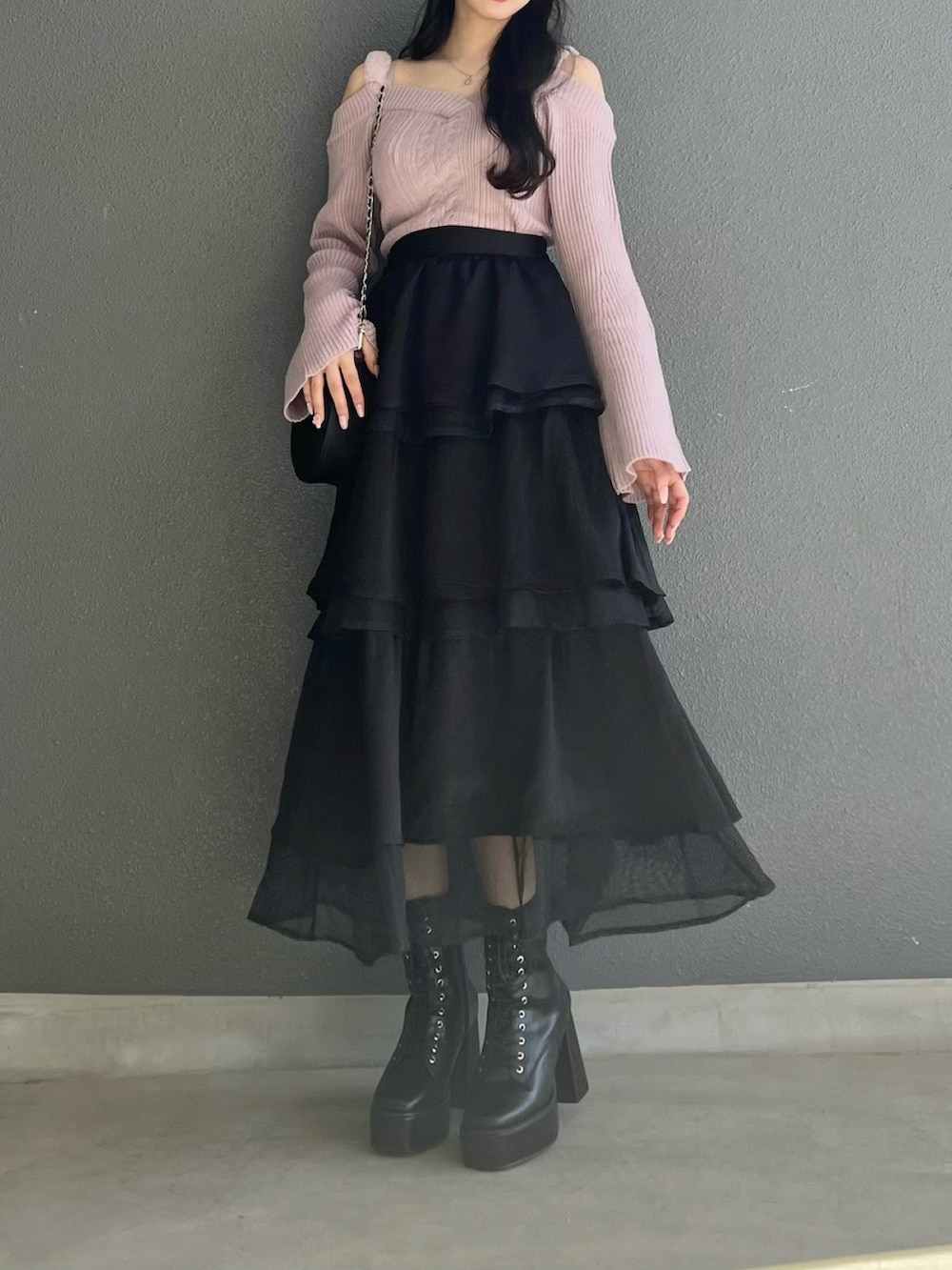 ピンク系のニット/セーター、ブラック系のスカート、ブラック系のブーツを着用したレディースの秋コーディネートの3枚目の写真