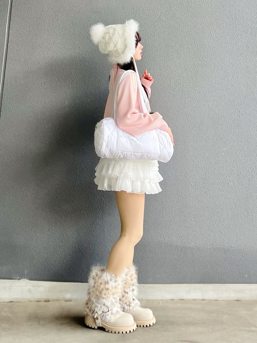 ホワイト系のスカート、ホワイト系のショルダーバッグ、ピンク系のニット/セーターを着用したレディースの春コーディネートの2枚目の写真