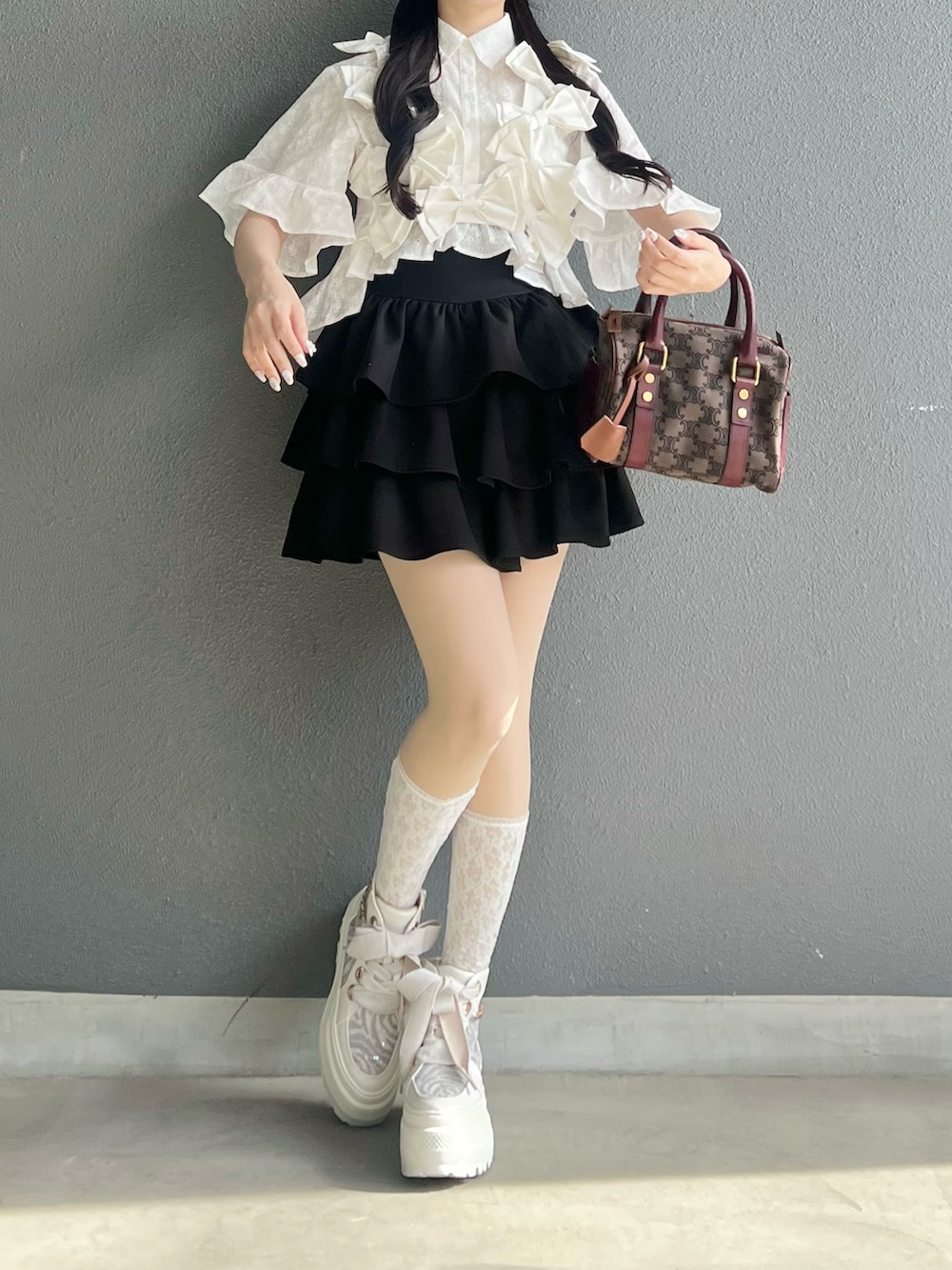 ブラック系のスカート、ホワイト系のベスト、ホワイト系のシャツ/ブラウスを着用したレディースの春コーディネートの2枚目の写真