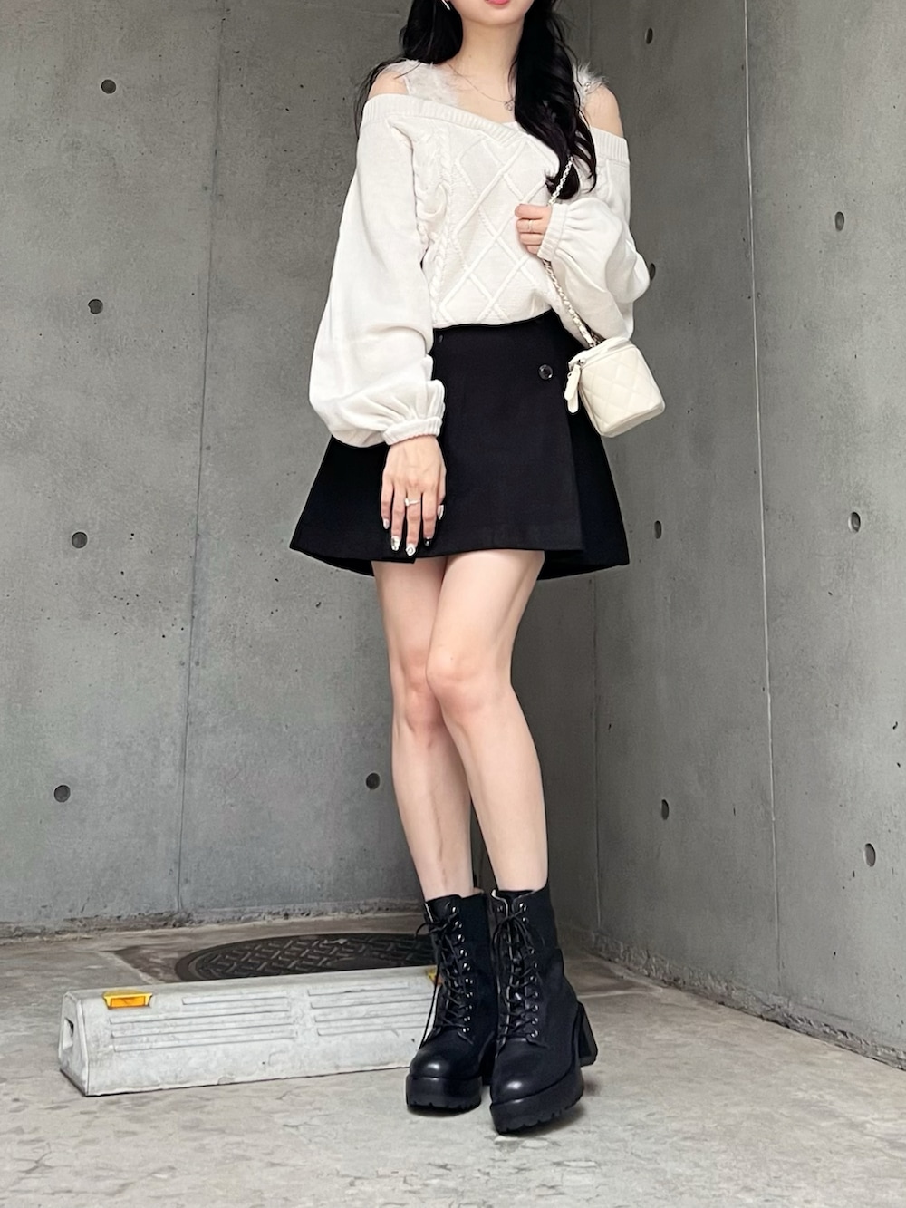 ホワイト系のニット/セーター、ブラック系のスカート、ブラック系のブーツを着用したレディースの秋コーディネートの4枚目の写真