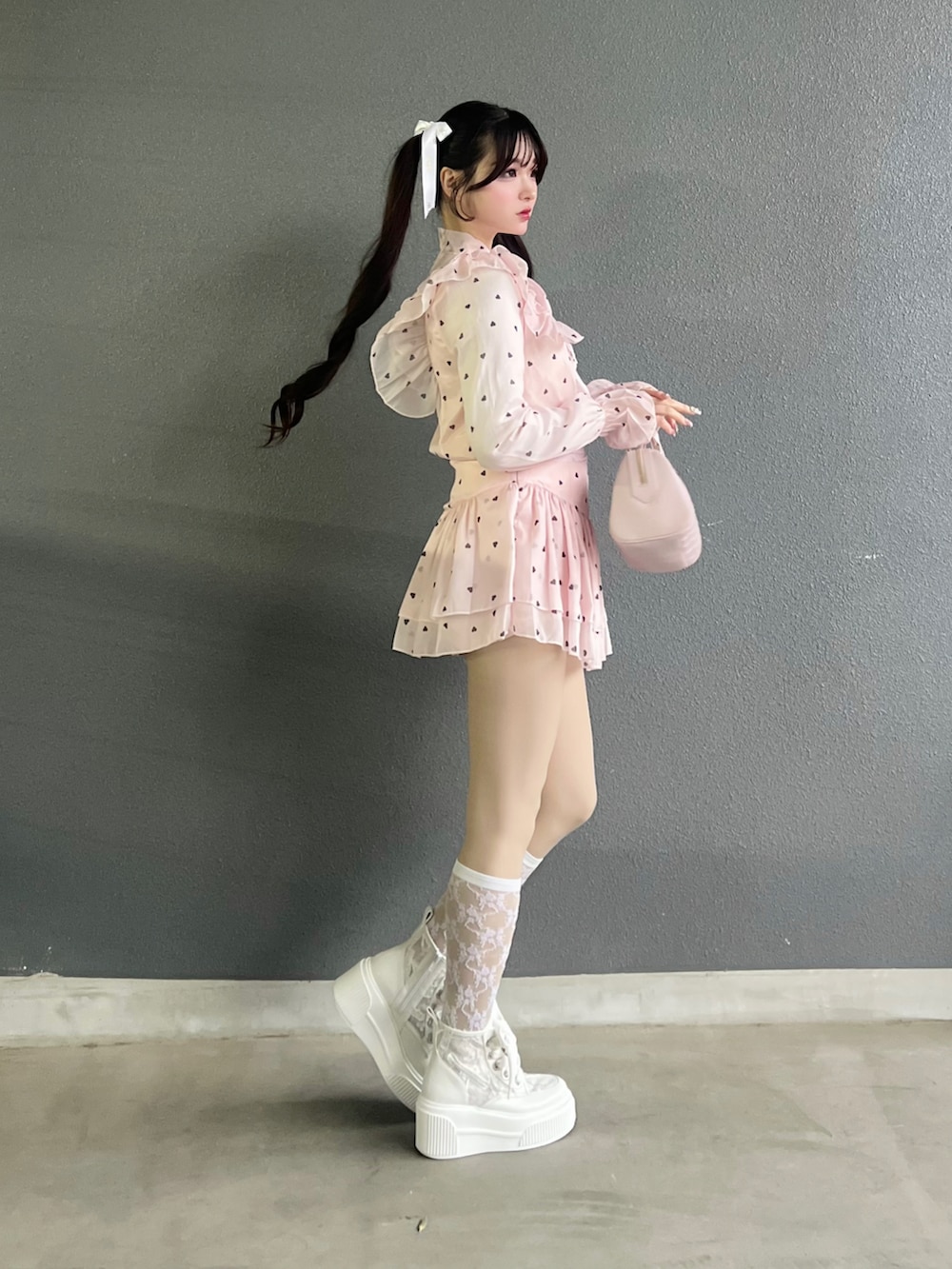 ホワイト系のスニーカー、ピンク系のトップス、ピンク系のバッグを着用したレディースの春コーディネートの3枚目の写真