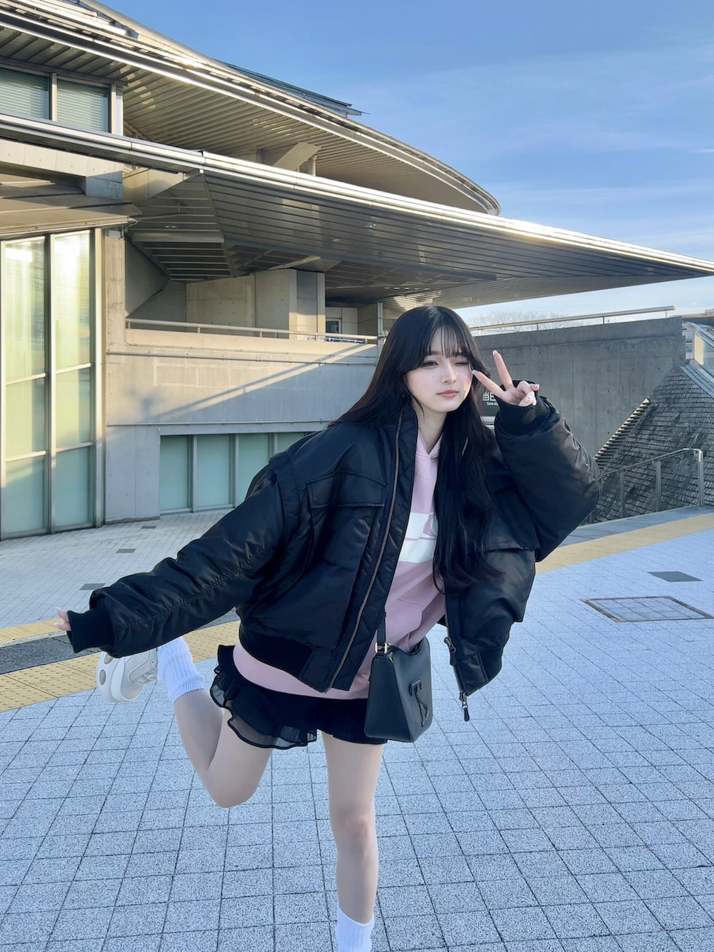 ホワイト系のスニーカー、ブラック系のショルダーバッグ、ピンク系のパーカーを着用したレディースの春コーディネートの4枚目の写真