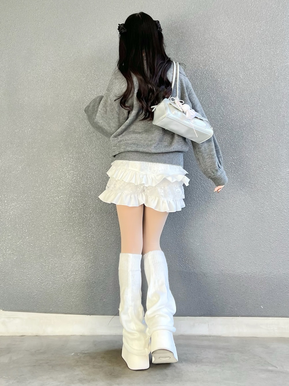 グレー系のニット/セーター、ホワイト系のパンツ、シルバー系のバッグを着用したレディースの冬コーディネートの3枚目の写真