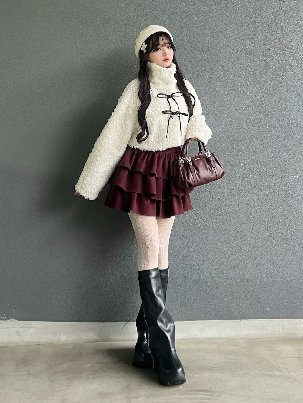 レッド系のバッグ、ブラック系のブーツ、ホワイト系のその他アウターを着用したレディースの秋コーディネートの2枚目の写真