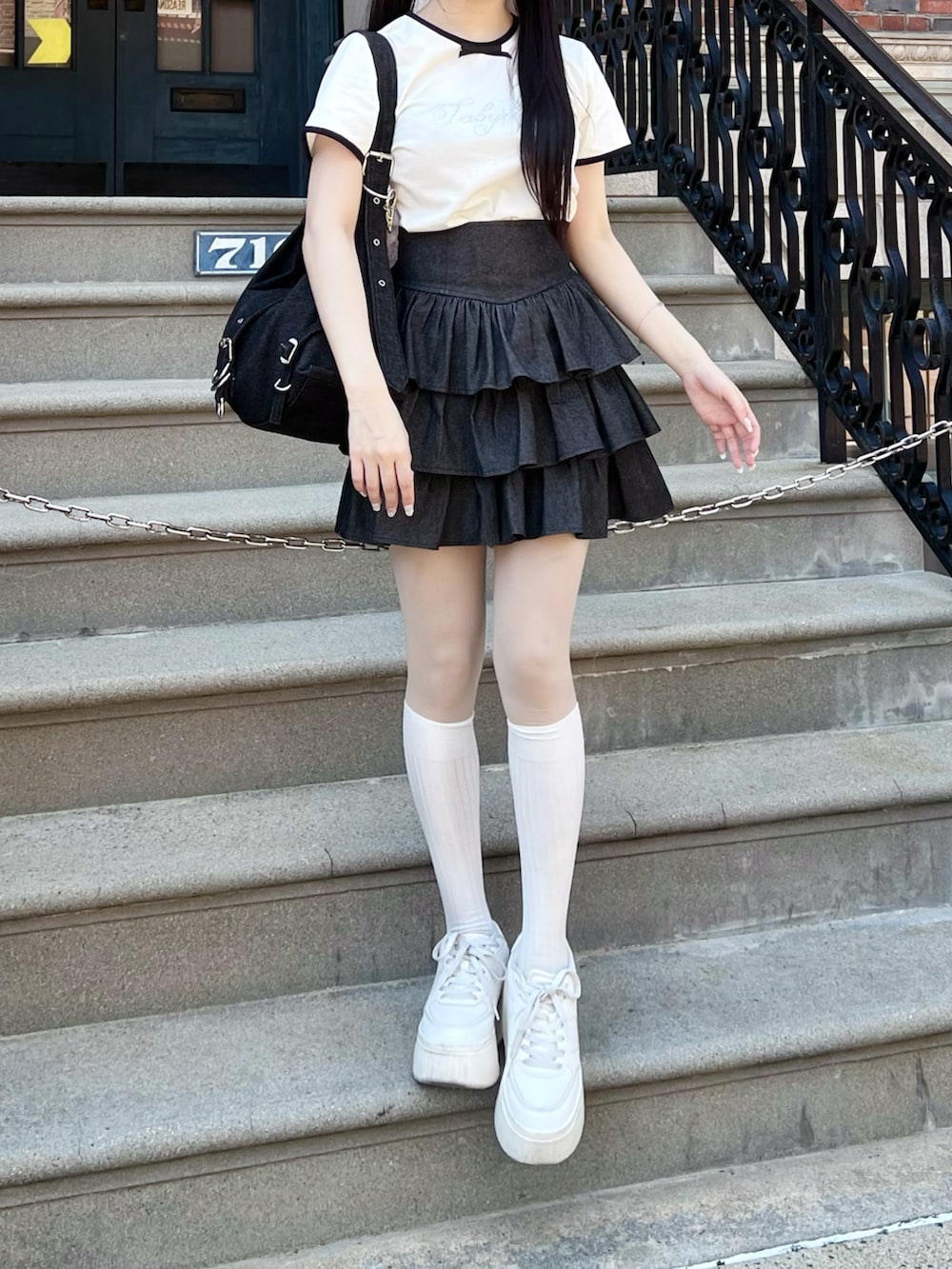 ホワイト系のシューズ、ブラック系のスカート、ブラック系のショルダーバッグを着用したレディースの春コーディネートの2枚目の写真