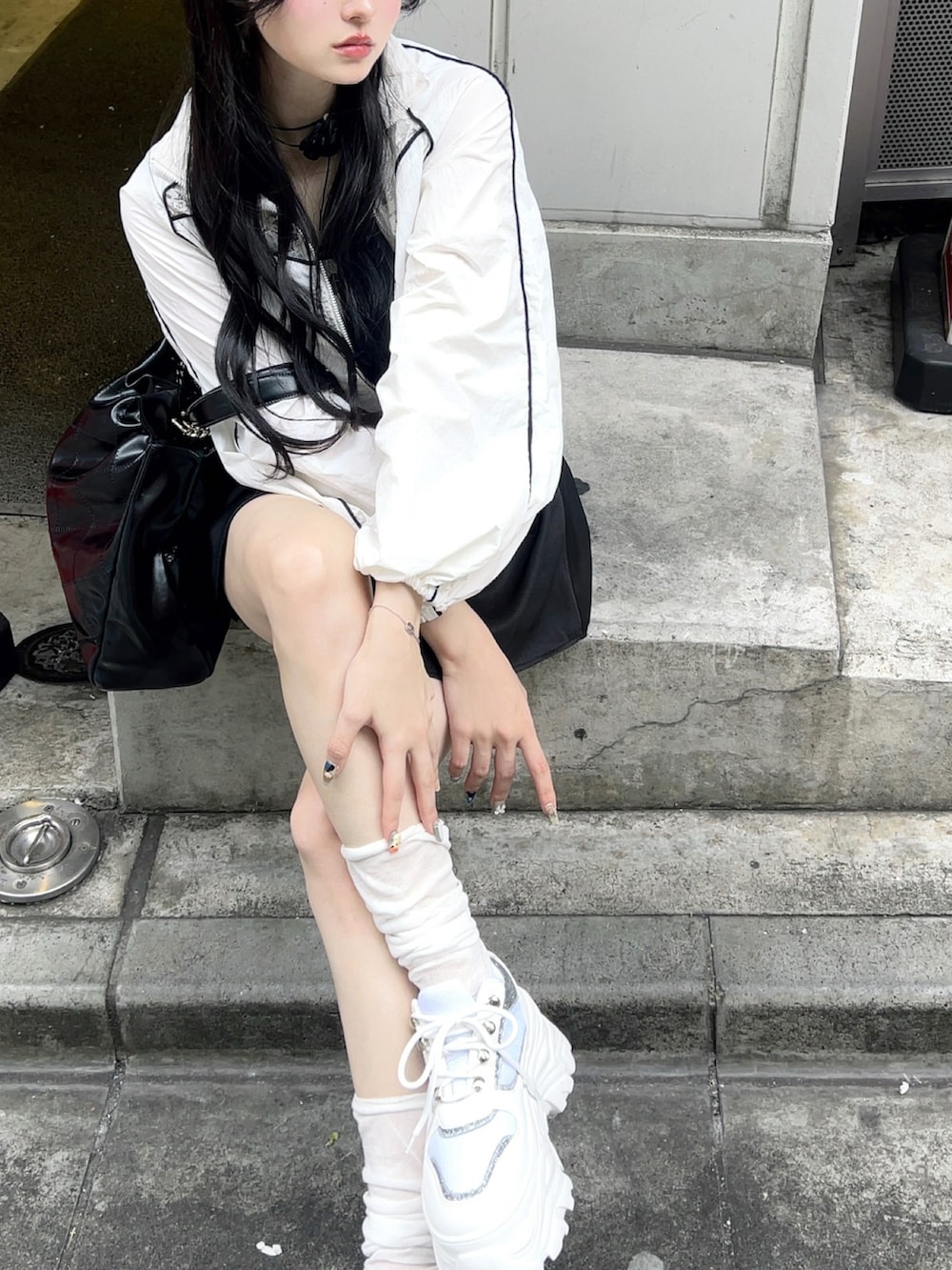 ホワイト系のベスト、ブラック系のスカート、ブラック系のバッグを着用したレディースの夏コーディネートの3枚目の写真