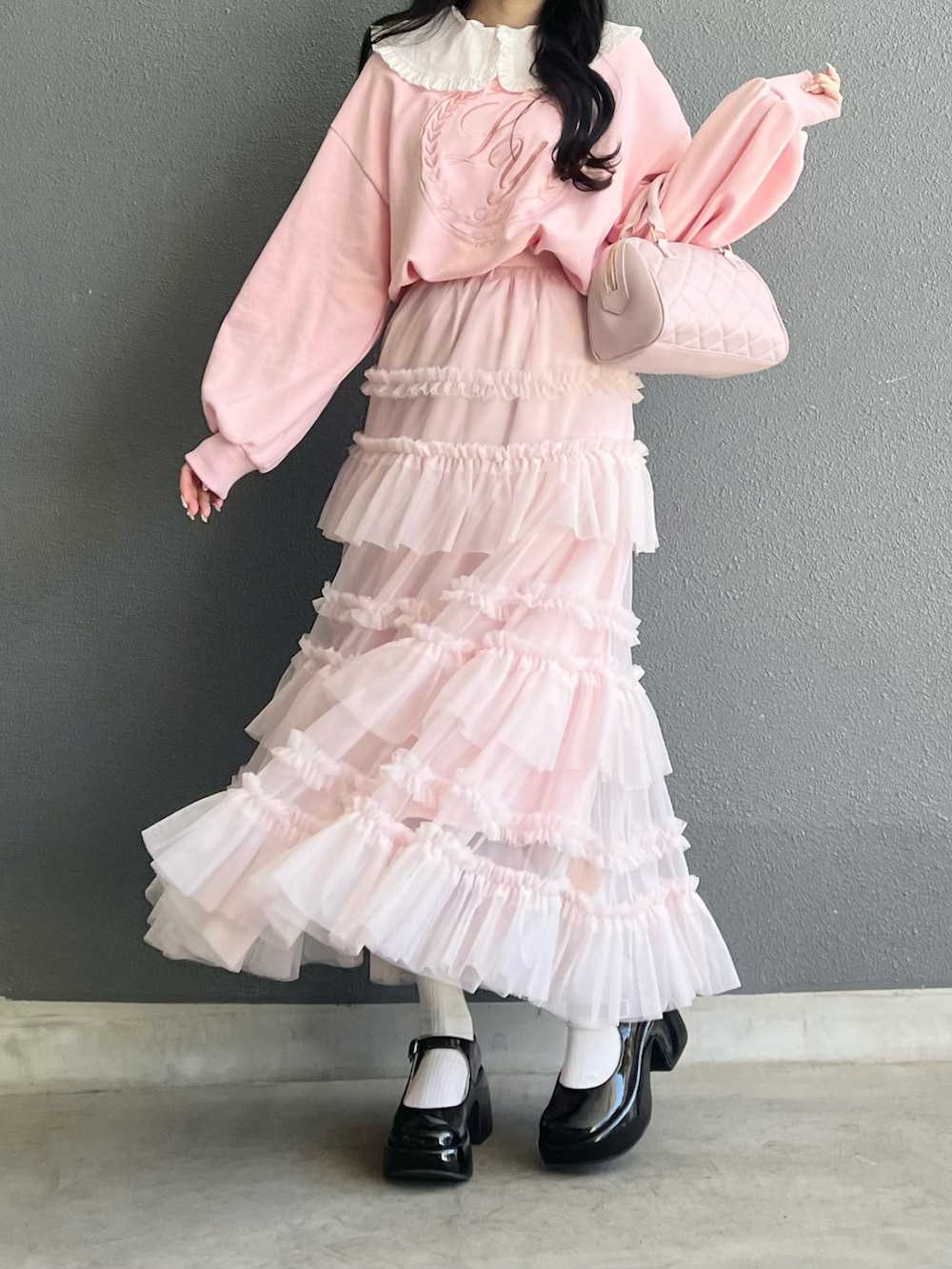 ブラック系のパンプス、ピンク系のバッグ、ピンク系のスウェットを着用したレディースの春コーディネートの3枚目の写真