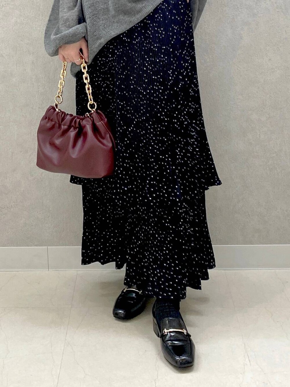 グレー系のニット/セーター、グレー系のスカート、ブラック系のローファーを着用したレディースの秋コーディネートの4枚目の写真