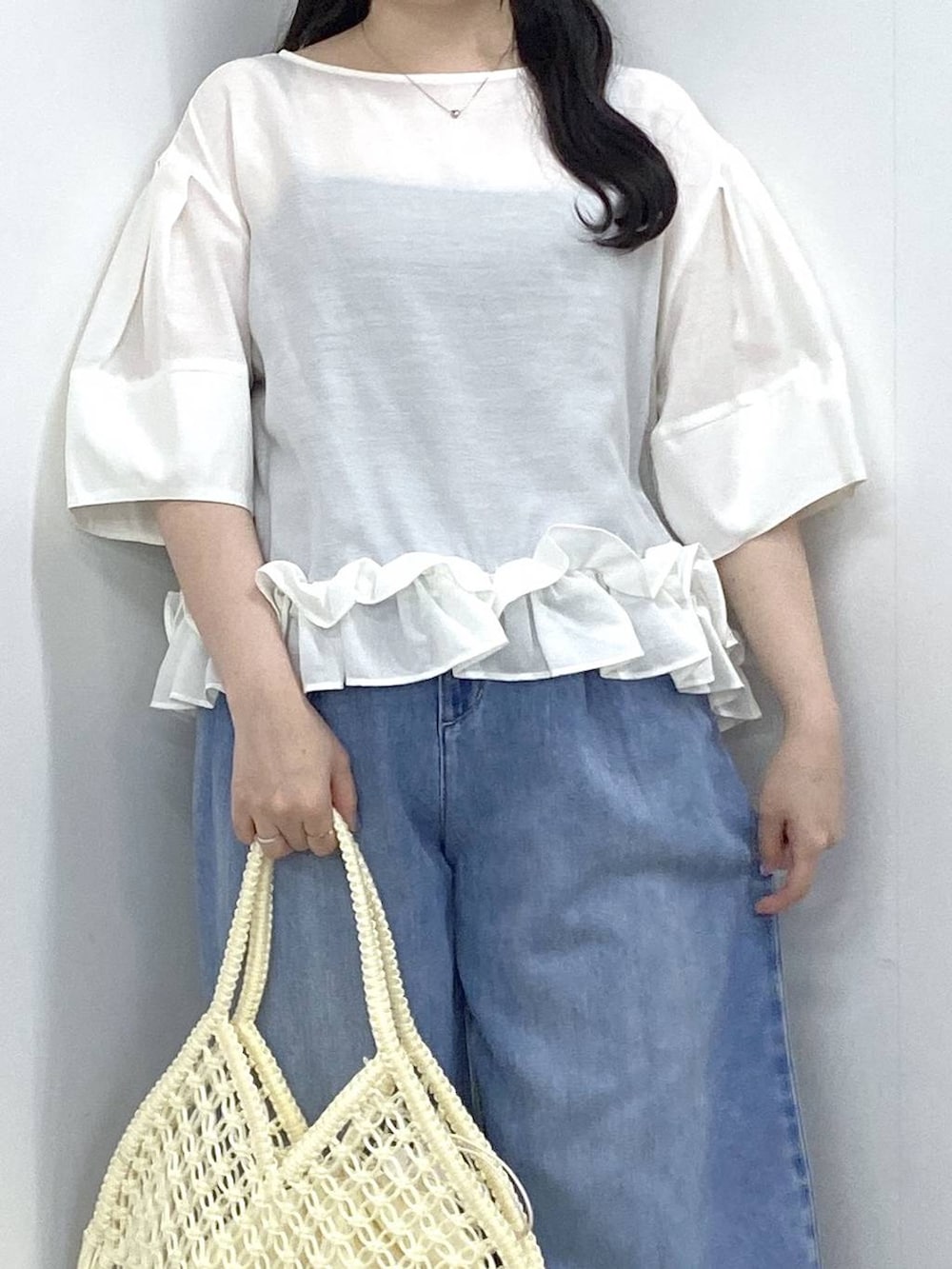 ホワイト系のハンドバッグ、ブルー系のデニムパンツ、ホワイト系のパンプスを着用したレディースの夏コーディネートの4枚目の写真