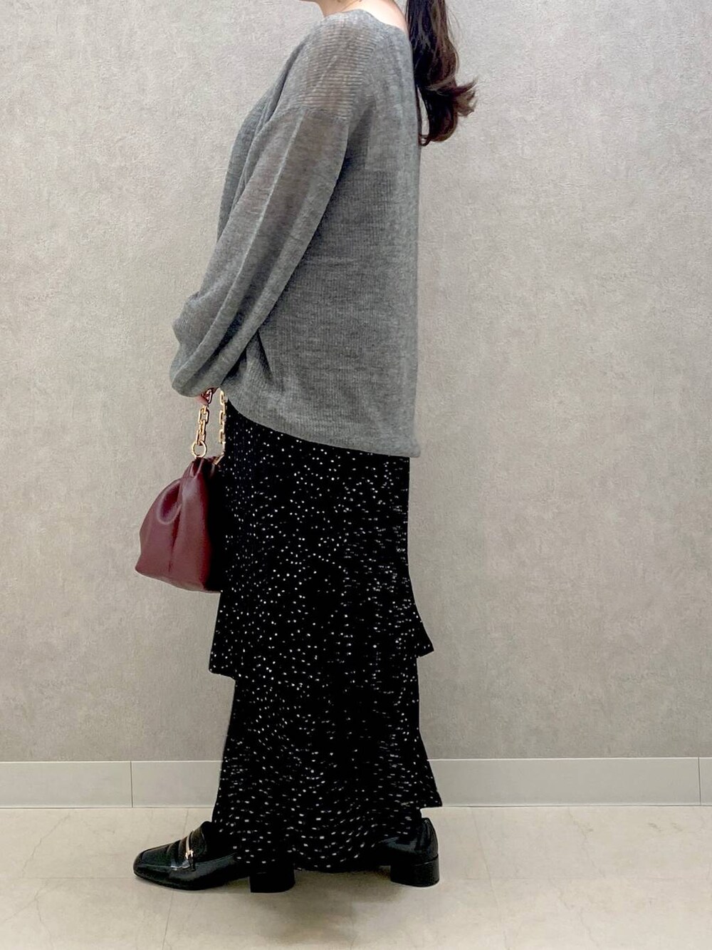 グレー系のニット/セーター、グレー系のスカート、ブラック系のローファーを着用したレディースの秋コーディネートの2枚目の写真
