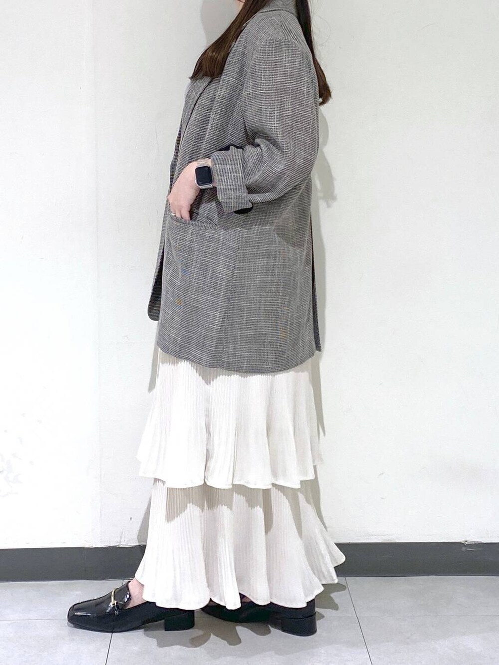 グレー系のタンクトップ、ホワイト系のスカート、ブラック系のテーラードジャケットを着用したレディースの夏コーディネートの2枚目の写真