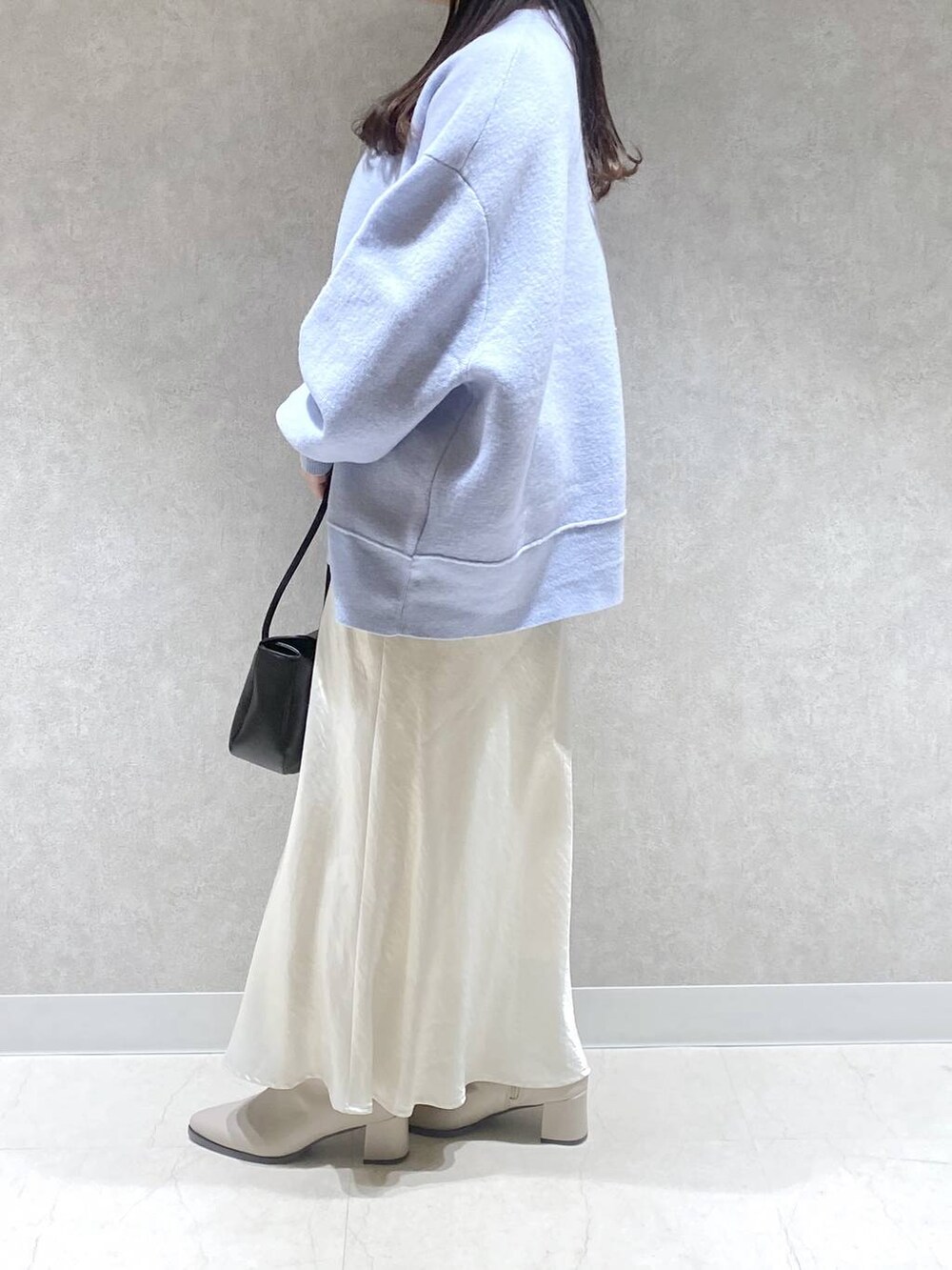 ベージュ系のブーツ、ホワイト系のスカート、ブルー系のニット/セーターを着用したレディースの冬コーディネートの2枚目の写真