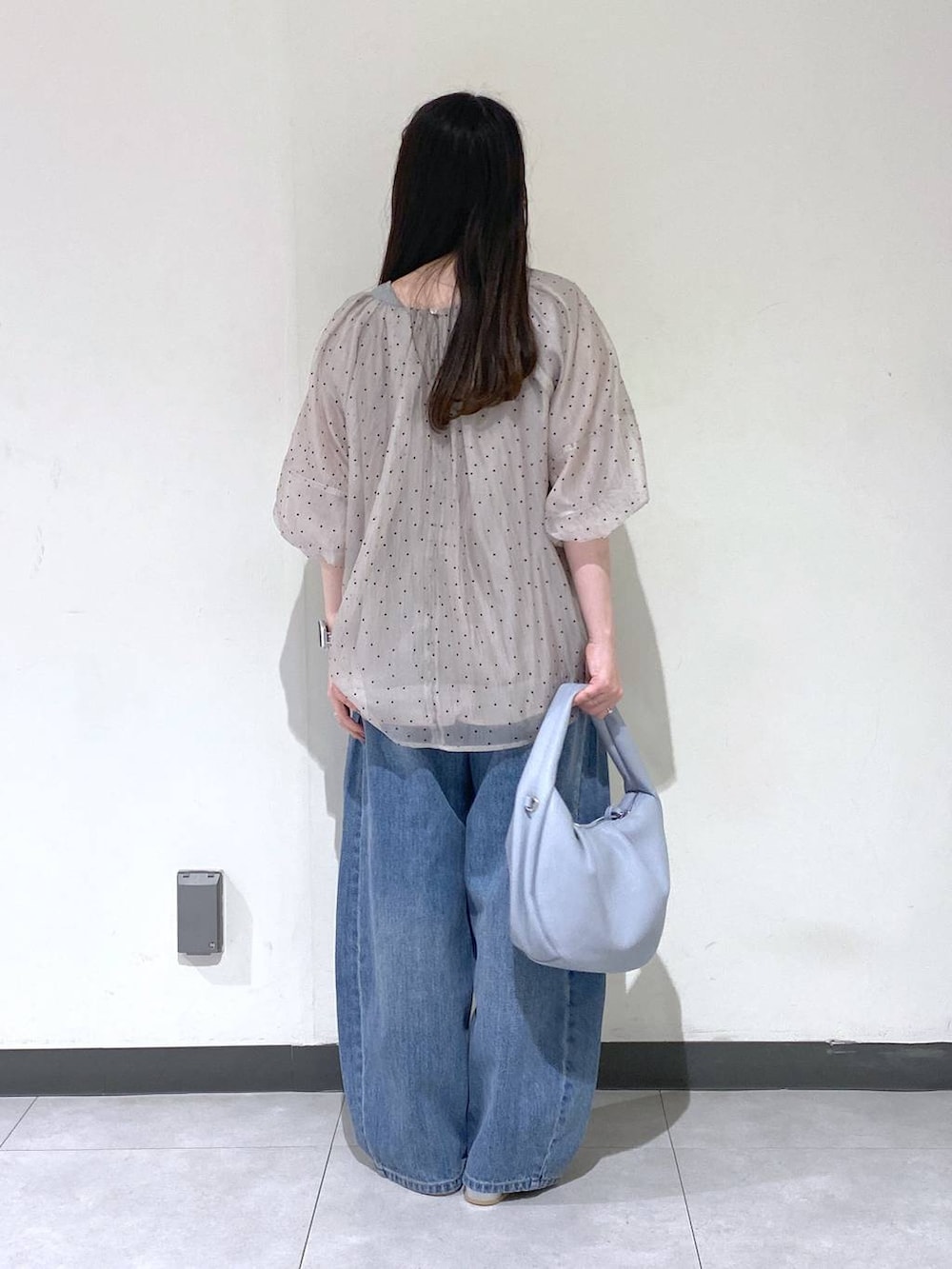 ブルー系のデニムパンツ、シルバー系のパンプス、ブルー系のハンドバッグを着用したレディースの秋コーディネートの3枚目の写真