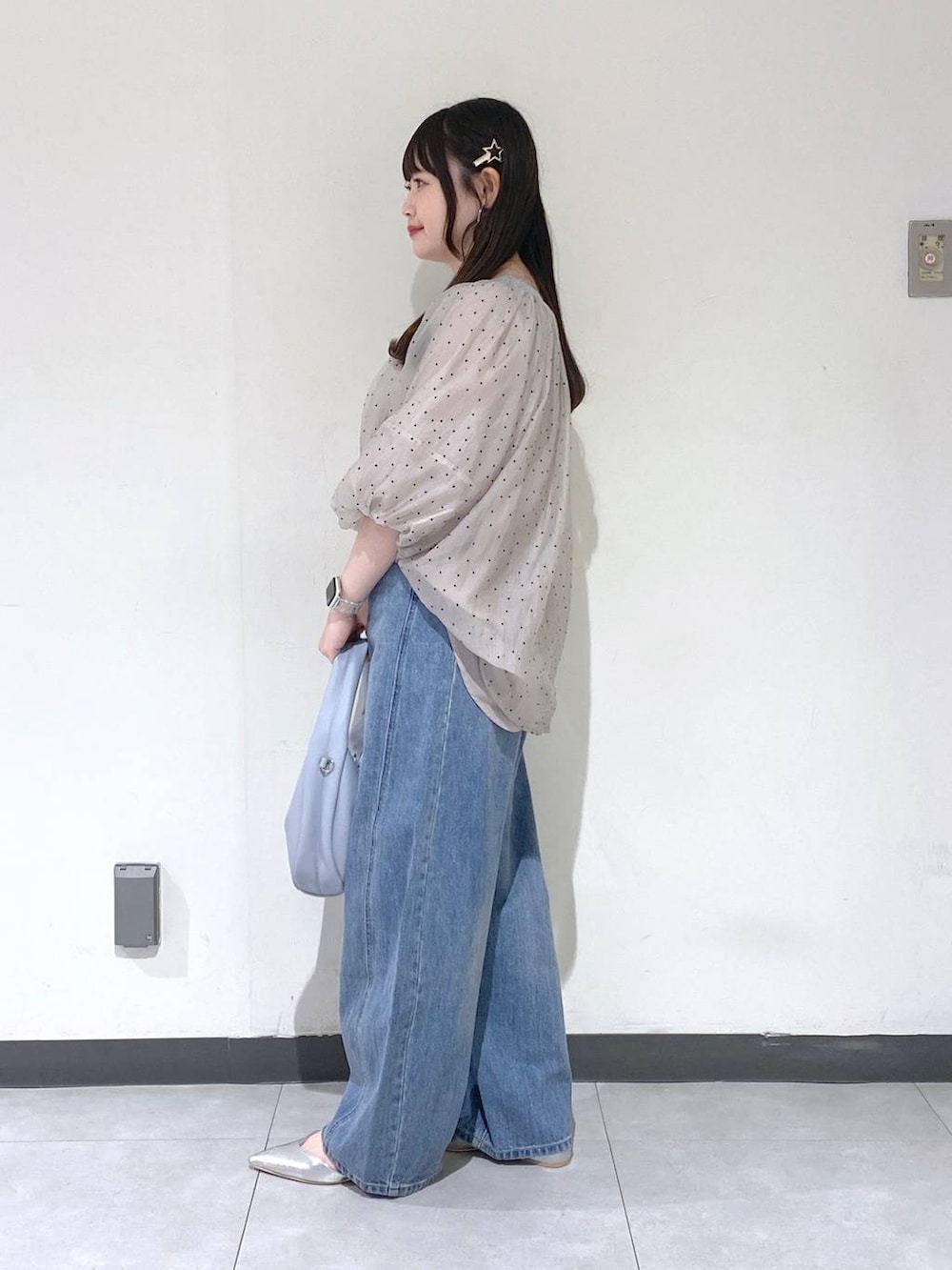 ブルー系のデニムパンツ、シルバー系のパンプス、ブルー系のハンドバッグを着用したレディースの秋コーディネートの2枚目の写真