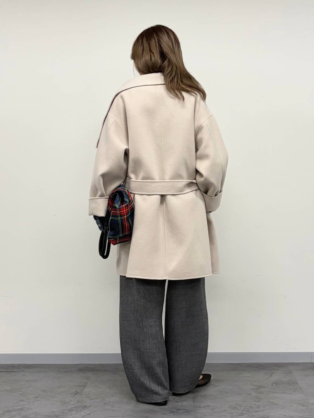 レッド系のトートバッグ、グレー系のその他パンツ、ベージュ系のステンカラーコートを着用したレディースの秋コーディネートの3枚目の写真