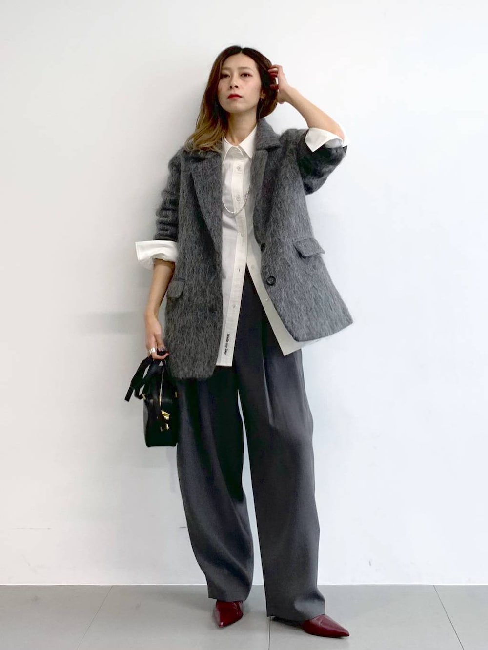 グレー系のその他パンツ、レッド系のブーツ、ブラック系のボストンバッグを着用したレディースの冬コーディネートの4枚目の写真