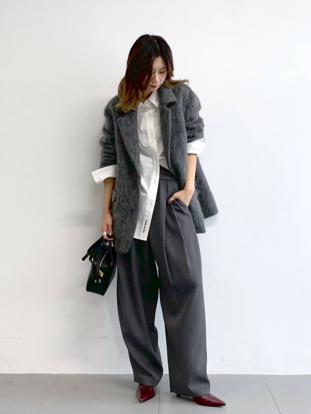 グレー系のその他パンツ、レッド系のブーツ、ブラック系のボストンバッグを着用したレディースの冬コーディネートの5枚目の写真