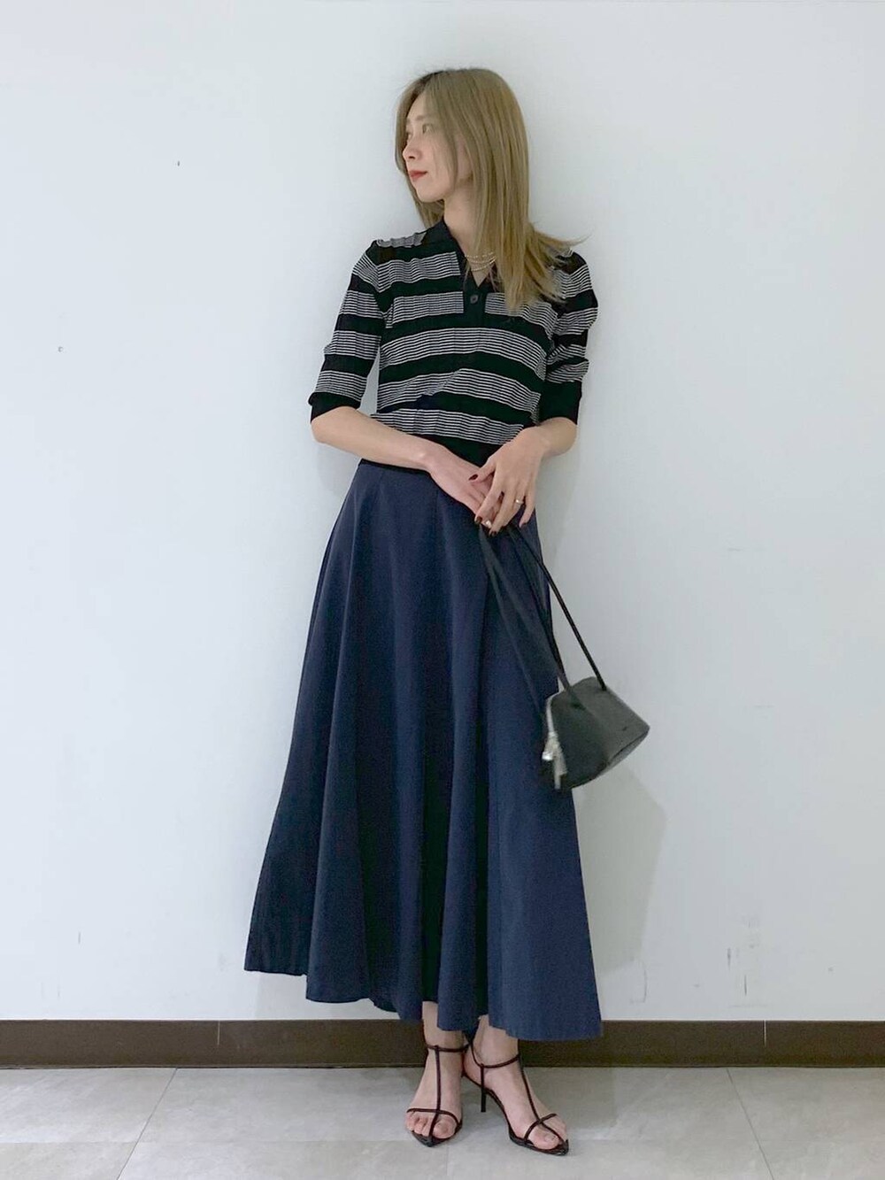 ブラック系のサンダル、ブラック系のハンドバッグ、ブラック系のポロシャツを着用したレディースの春コーディネートの2枚目の写真