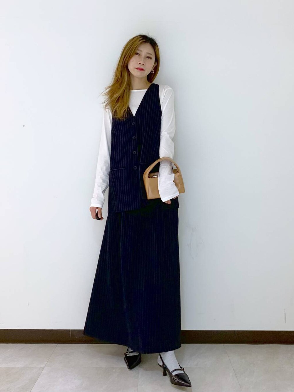 ブルー系のベスト、ブルー系のスカート、ホワイト系のTシャツ/カットソーを着用したレディースの秋コーディネートの4枚目の写真