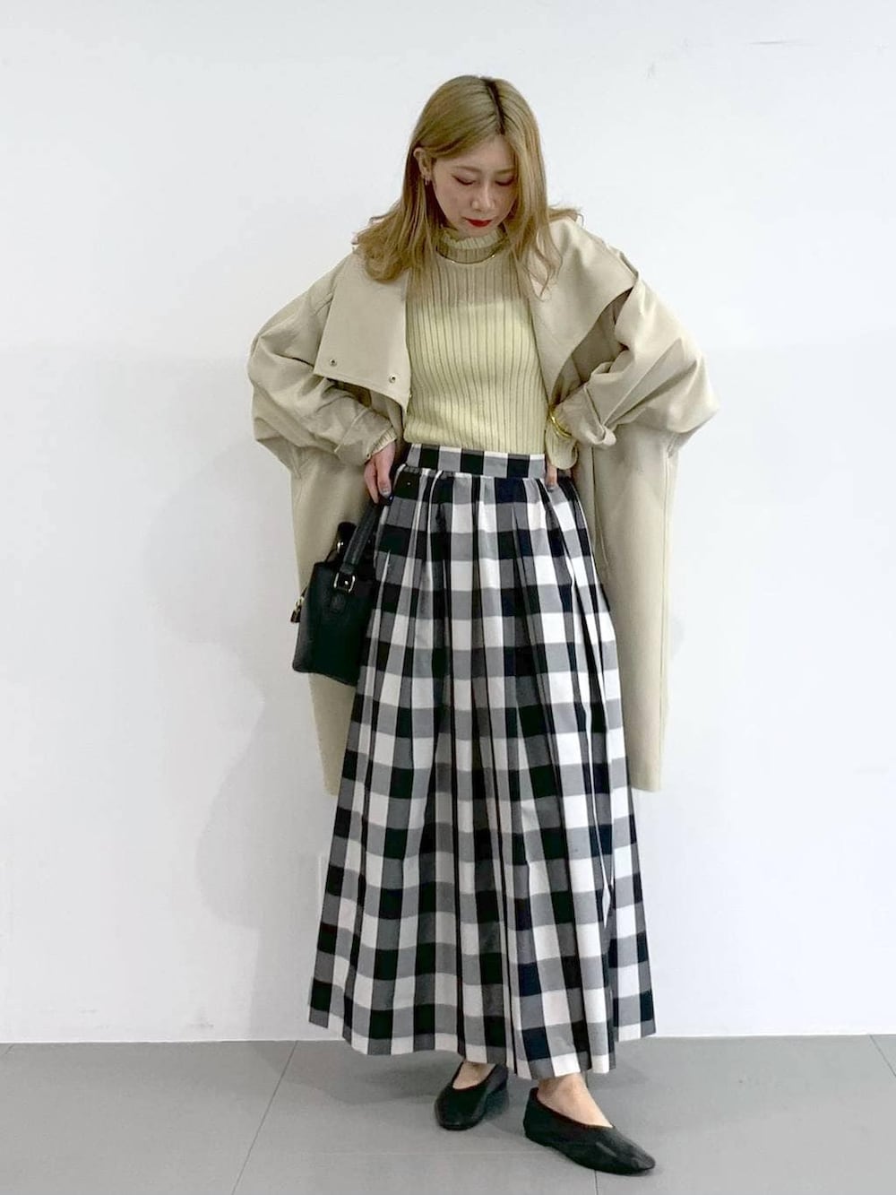 イエロー系のニット/セーター、ベージュ系のその他アウター、ブラック系のスカートを着用したレディースの冬コーディネートの2枚目の写真