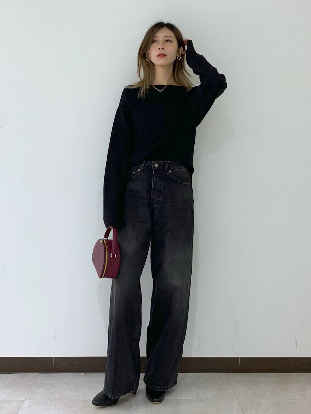 ブラック系のニット/セーター、ブラック系のデニムパンツ、レッド系のハンドバッグを着用したレディースの秋コーディネートの5枚目の写真