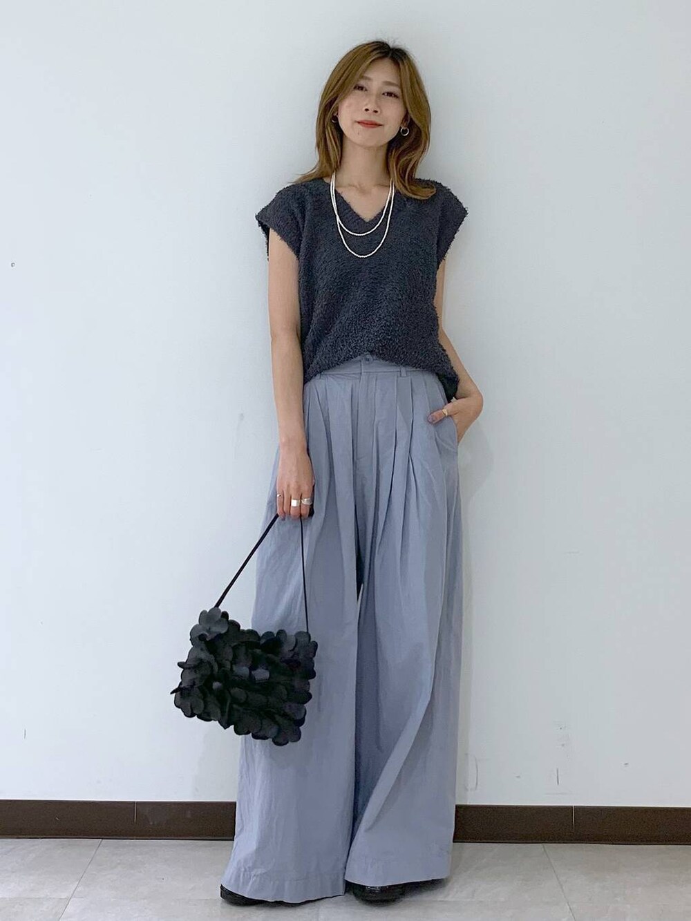 グレー系のニット/セーター、ブラック系のショルダーバッグ、ブラック系のスニーカーを着用したレディースの夏コーディネートの5枚目の写真