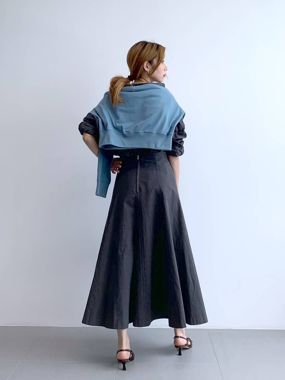 ブルー系のTシャツ/カットソー、シルバー系のショルダーバッグ、グレー系のスカートを着用したレディースの秋コーディネートの4枚目の写真