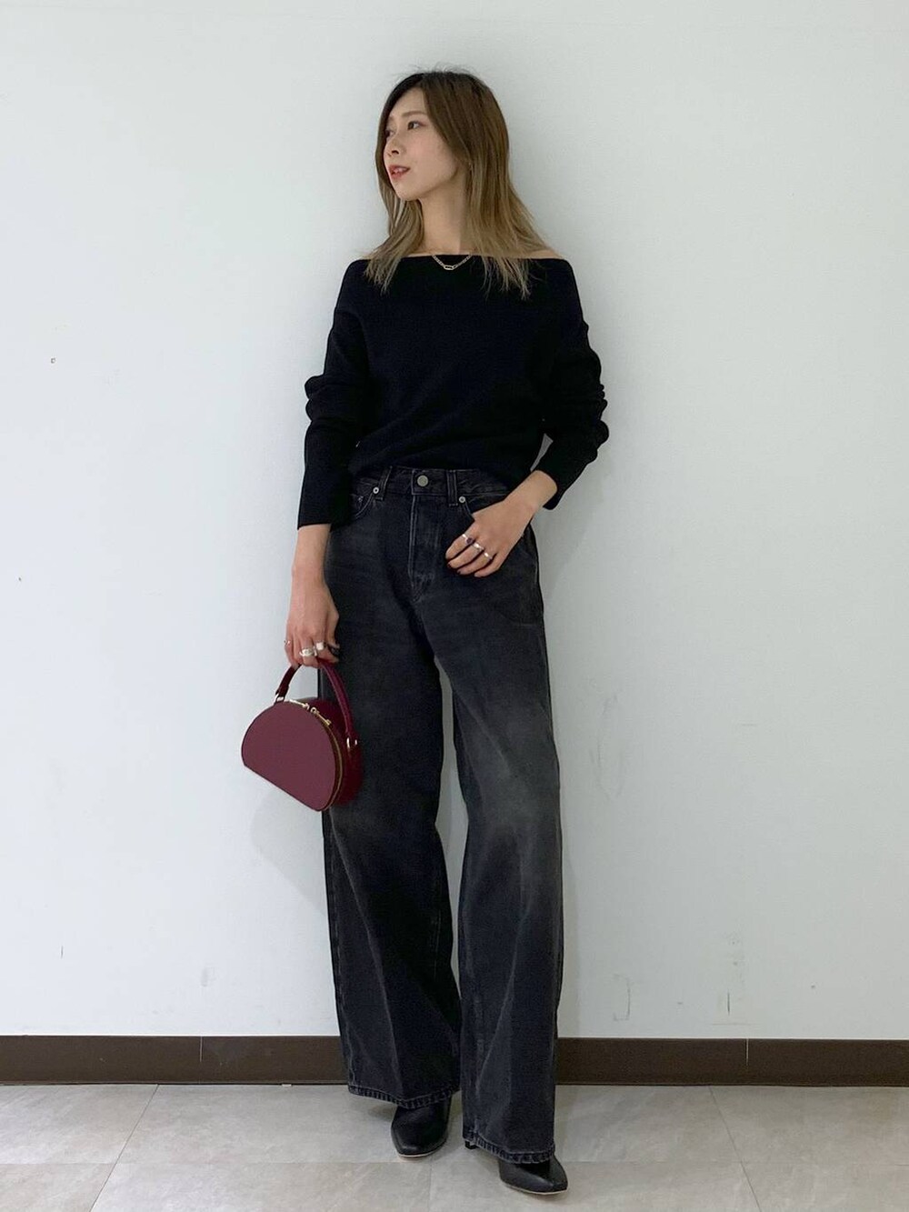 ブラック系のニット/セーター、ブラック系のデニムパンツ、レッド系のハンドバッグを着用したレディースの秋コーディネートの2枚目の写真