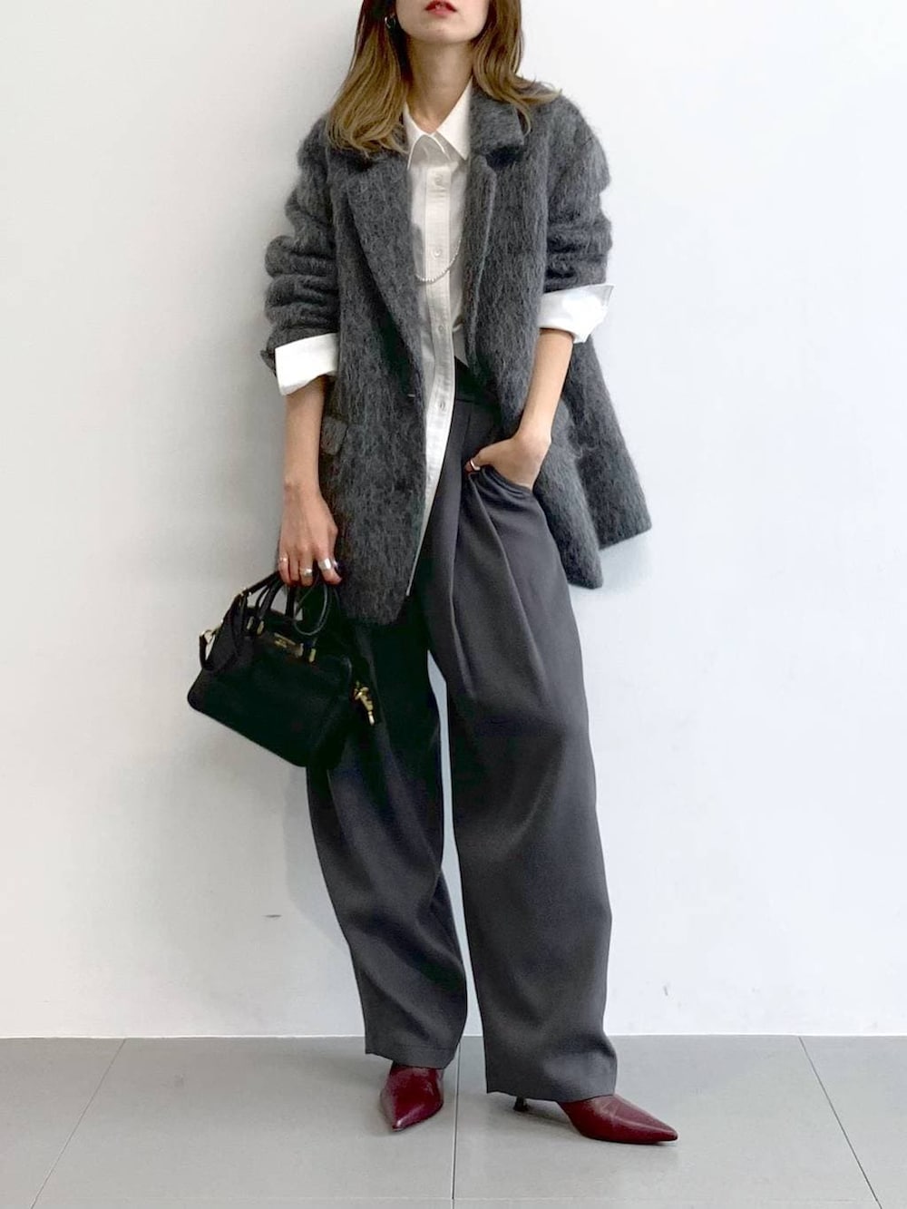 グレー系のその他パンツ、レッド系のブーツ、ブラック系のボストンバッグを着用したレディースの冬コーディネートの6枚目の写真