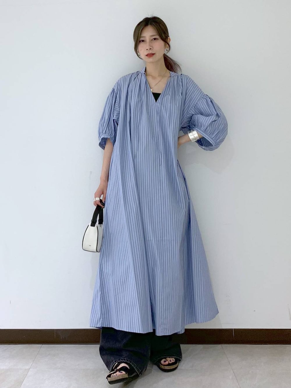 ブラック系のサンダル、ブラック系のデニムパンツ、ブルー系のワンピースを着用したレディースの夏コーディネートの2枚目の写真